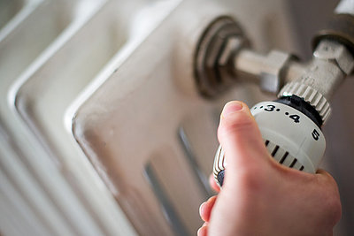 Foto: Hand dreht am Thermostat einer Heizung