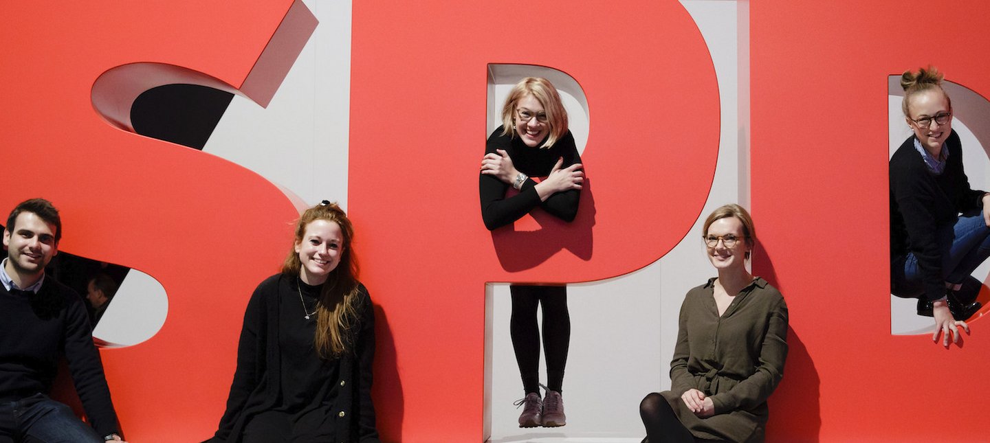 Foto: Junge Menschen sitzen am SPD-Logo