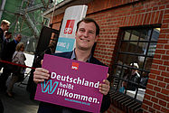 Imo/Photothek Foto: Mann hält Willkommen heißen Schild
