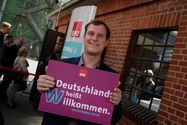 Imo/Photothek Foto: Mann hält Willkommen heißen Schild
