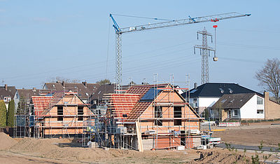 Foto: Einfamilienhäuser stehen im Rohbau in einem Neubaugebiet 