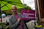 Imo/Photothek Foto: Mann hält Willkommen heißen Schild