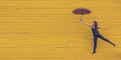 Foto: Frau springt mit Regenschirm in die Luft