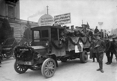 Foto: Blaskapelle mit Soldaten auf Auto mit Wahlplakaten, u.a. mit Text: "Für die Regierung Ebert-Scheidemann, gegen den Terror"