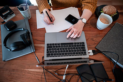 Foto: Frau sitzt mit einem Laptop an einem Tisch im Homeoffice