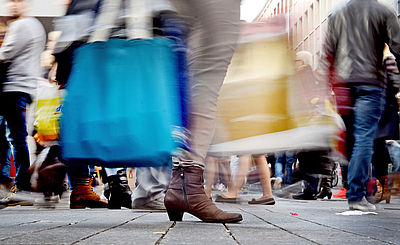 Foto: Passanten tragen ihre Einkäufe in Taschen durch die Fußgängerzone