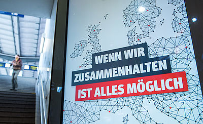 Foto: "Wenn wir zusammenhalten ist alles mšglich" steht an einem Bahnhof auf einer Werbetafel.