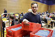 Foto: Ein Freiwilliger nimmt ein Kasten mit Stimmunterlagen zur Auszählung