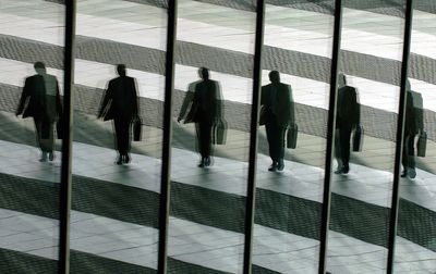 Foto: Ein Mann mit Aktentasche geht in Bonn ins Büro und spiegelt sich dabei in den Glasscheiben der Post-Towers (Archivfoto, Illustration zum Thema Manager)