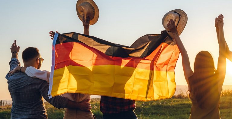 getty Foto: Junge Menschen mit Deutshcladnfahne jubeln bei Sonnenuntergang