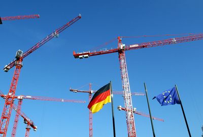 Kräne hinter einer Deutschland- und einer EU-Flagge. (Foto: dpa)