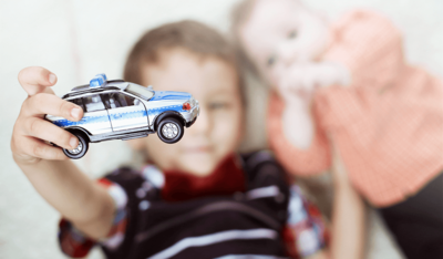 Foto: Kind hält Polizeiwagen neben kleinem Bruder