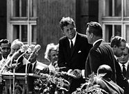 dpa Foto: John F. Kennedy (M) und Willy Brandt (r) vor dem Schöneberger Rathaus in Berlin am 26. Juni 1963