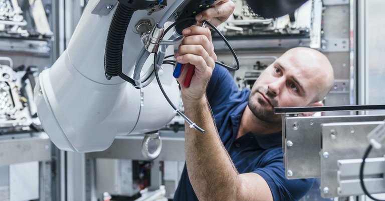 Foto: Mann arbeitet an einem Industrieroboter in einer modernen Fabrik 