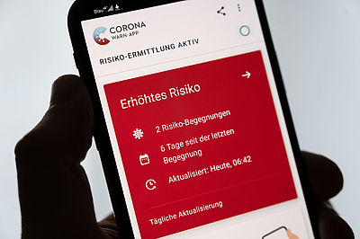  Foto: Smartphone, auf dem die Corona-Warn-App der Bundesregierung ein erhöhtes Risiko anzeigt
