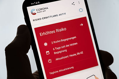 Foto: Smartphone, auf dem die Corona-Warn-App der Bundesregierung ein erhöhtes Risiko anzeigt